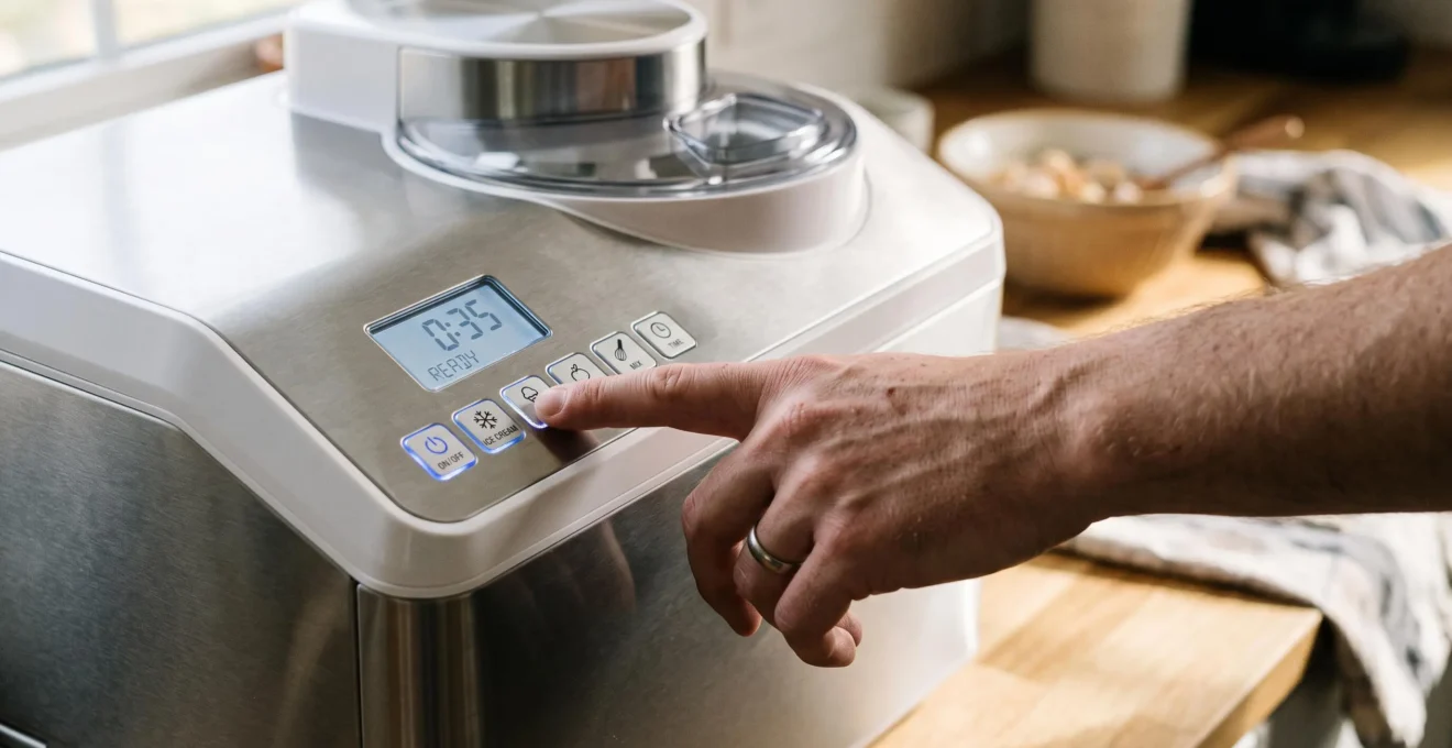 Main sélectionnant un programme automatique sur le panneau de contrôle d'une machine à glace domestique moderne.